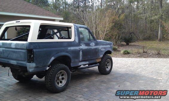 Dark blue and white Ford Bronco with aftermarket wheels and tires, seen from the side