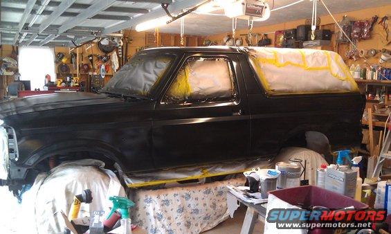 Black Ford Bronco undergoing paintwork in a garage, side view