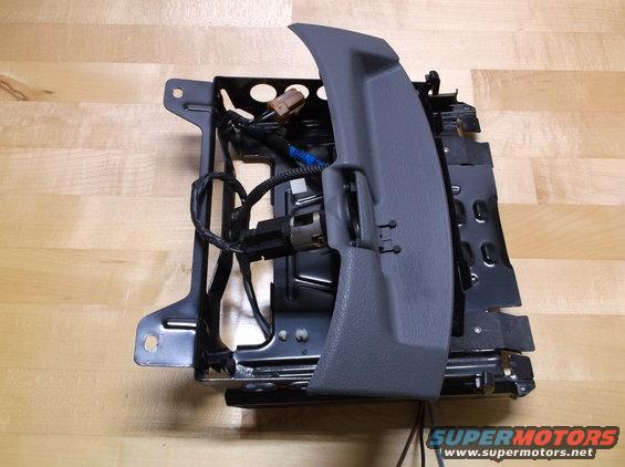 Gray plastic trim and metal seat frame with wiring on a wooden surface