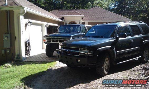 Black 1992 Ford Bronco with lifted suspension and aftermarket bumper parked next to a dark SUV