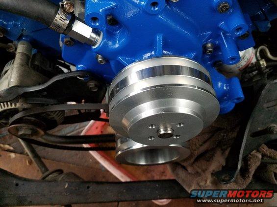 Polished aluminum water pump pulley on blue engine block