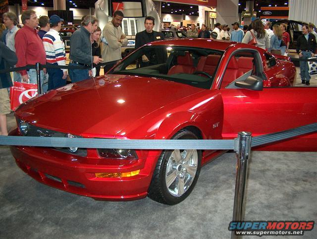 Red coupe with door open, on display at an auto show. Interior is red