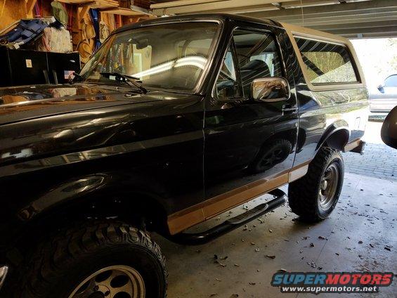 Black Ford Bronco with tan trim and running boards parked in a garage