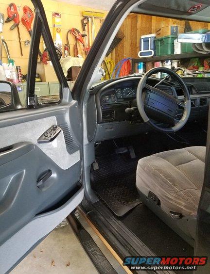 Interior of a gray 1992 Ford Bronco showing the dashboard, steering wheel, driver's seat, and door panel