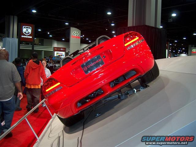 Red Dodge convertible on display at an auto show, rear view