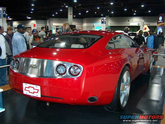 Red concept car rear view with chrome strip, dual round taillights, and Chevrolet emblem