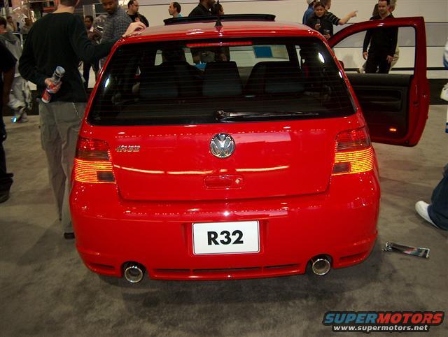 Red Volkswagen Golf R32 with R32 badge on the rear, dual exhaust pipes, and open driver's door