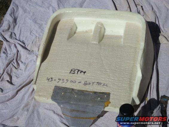 Foam part with handwritten text 'BTM 43-73700 - BOTTOM' and a metal bracket