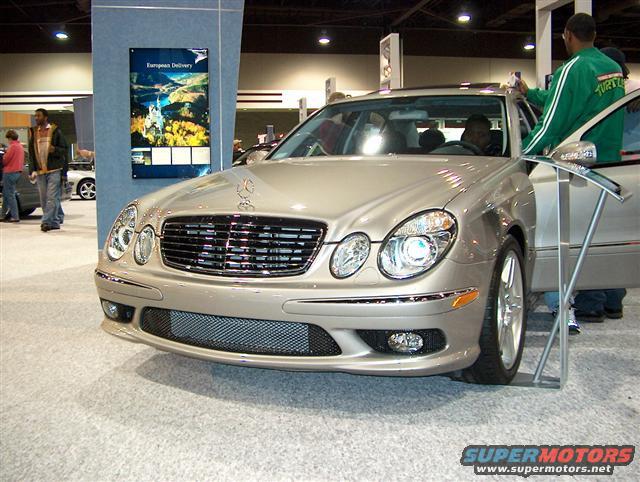 Silver Mercedes-Benz E-Class sedan with a prominent grille and headlights, viewed from the front-right