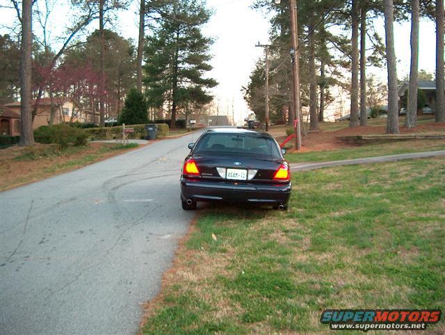 Dark blue 2001 Ford Crown Victoria parked on the right side of a residential street, rear view