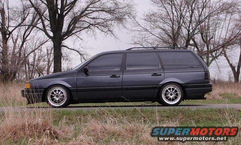Dark gray station wagon with tinted windows and aftermarket wheels parked on a roadside