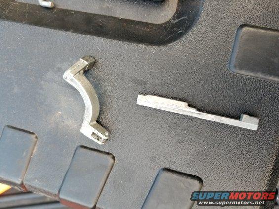 Two metal automotive parts on a textured surface