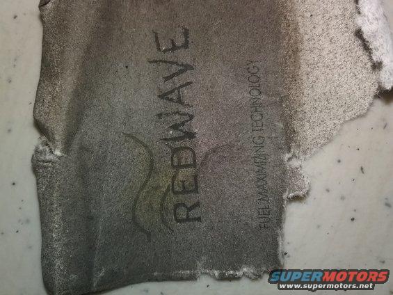 Torn piece of material with REDWAVE and FUEL MAXIMIZING TECHNOLOGY printed on it