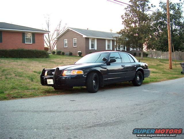 Black 2001 Ford Crown Victoria with push bar parked on street