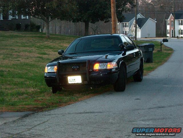 Black 2001 Ford Crown Victoria with a push bar, parked on a residential street