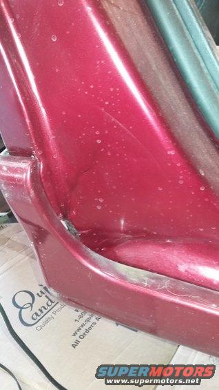 Red car panel with water spots and minor damage near a green trim piece