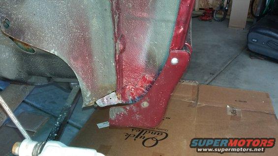 close-up of red metal bracket attached to car's undercarriage, with tools and boxes nearby