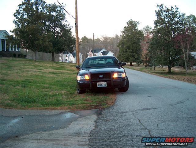 Black 2001 Ford Crown Victoria police car parked on a residential street, front quarter view