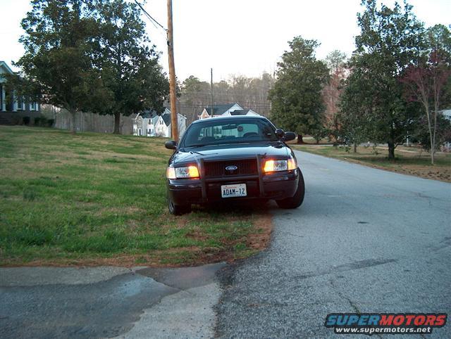 Front view of a black 2001 Ford Crown Victoria with a push bar and license plate ADAM-12