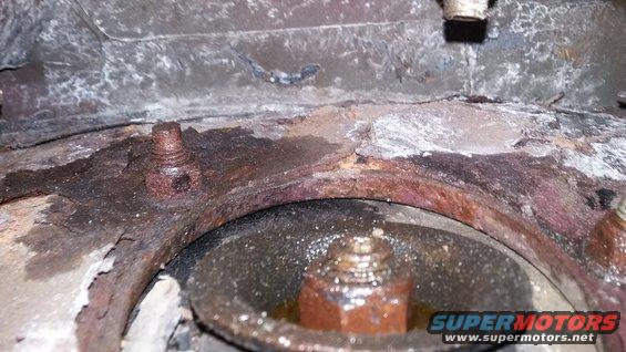 rusted metal bracket with bolts and a circular component below