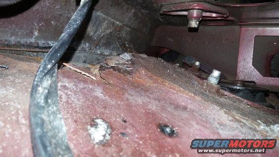 Close-up of heavily rusted metal and a black wire bundle under a vehicle