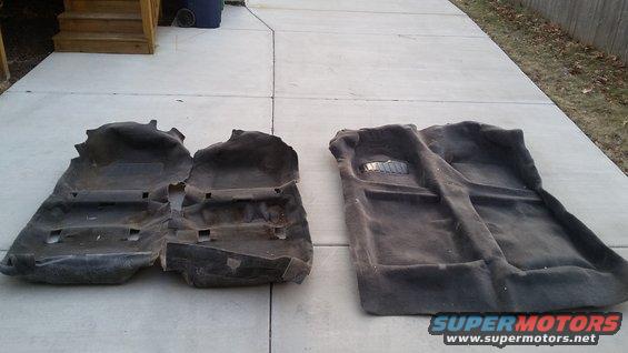 Two dark gray car floor mats laid out on a concrete driveway