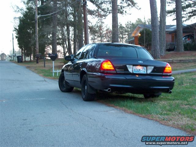 Dark blue 2001 Ford Crown Victoria parked on the side of a rural road, rear view