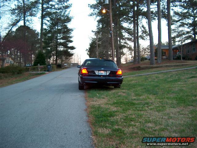 Dark sedan parked on a residential street, rear view. License plate reads ADAN-72