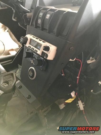 Close-up of an off-road vehicle's dashboard with a CB radio and start button