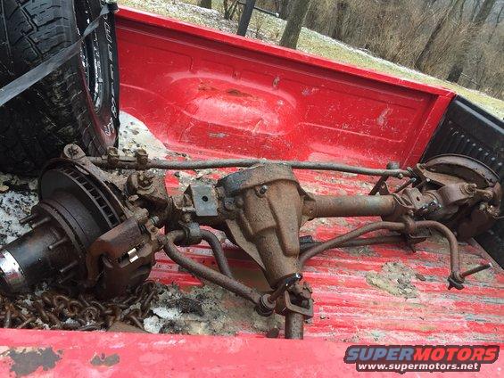 Front axle assembly with disc brakes and suspension components, loaded in a red pickup truck bed