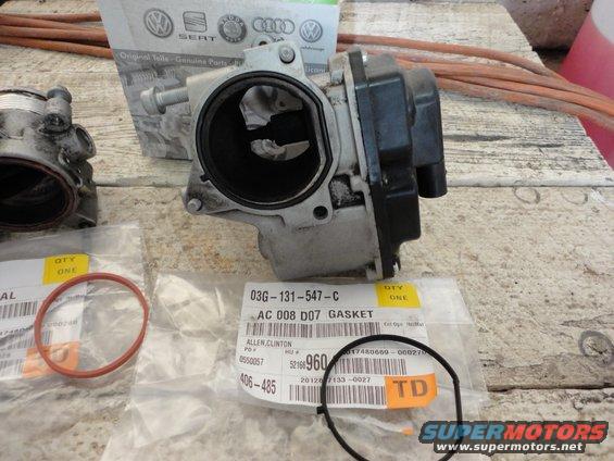 Throttle body and two gaskets on a workbench. Part number 03G-131-547-C is visible