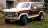 Two-tone brown and white 1980 Ford Bronco with woodgrain paneling, lifted suspension, and large tires