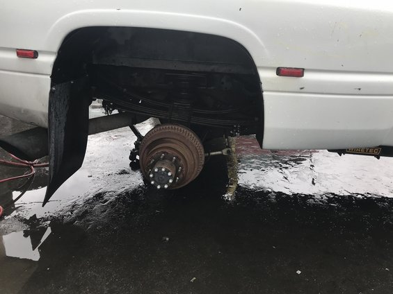 1997 Dodge 3500 rear axle with leaf springs and brake drum visible. Mud flap is in place