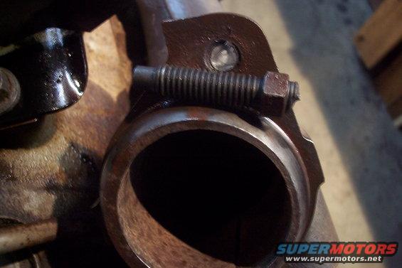 Close-up of an exhaust pipe flange connection with a bolt and spring