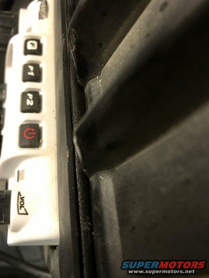 Close-up of a white plastic panel with buttons labeled P1, P2, and a power symbol, next to a black textured surface