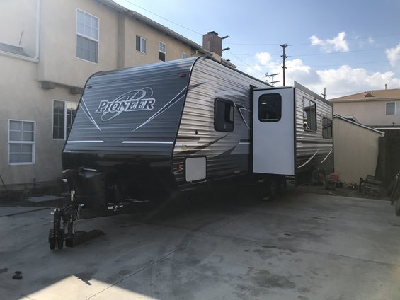 Pioneer travel trailer parked in a driveway with the door open