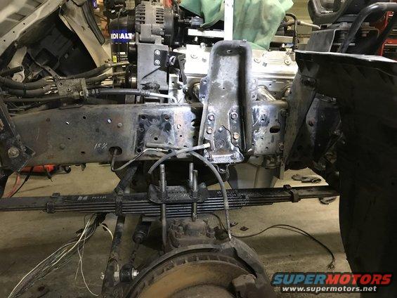 Close-up of truck chassis showing engine block, alternator, leaf springs, and brake assembly