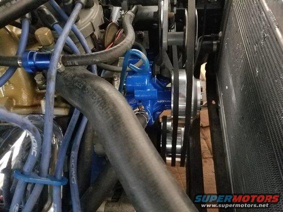 Engine bay with blue water pump and belts near radiator