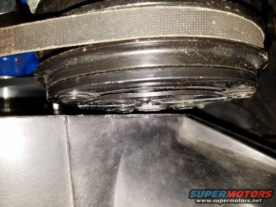 Close-up of a serpentine belt and pulley system, possibly an AC compressor clutch