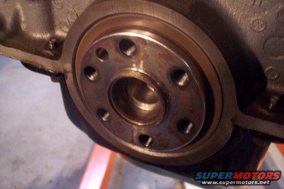Close-up of a rusty crankshaft flange with six bolt holes