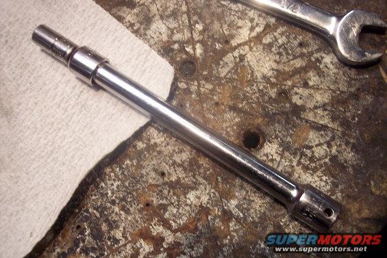 Chrome socket extension and 1/2 inch wrench on a workbench