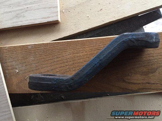 Dark metal part with a bend, resting on wood planks