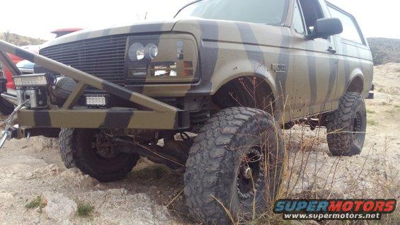 Camouflaged 1996 Ford Bronco with large tires and a winch on the front bumper