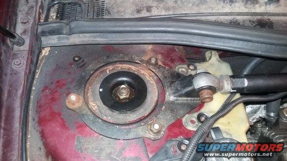 Close-up of a vehicle's strut mount assembly, showing rust and wear