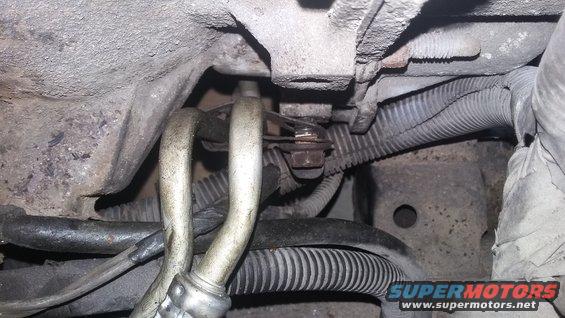 Close-up of hoses and wiring under a vehicle, possibly part of the AC system