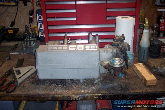 Ford 5.8 EFI intake manifold on a workbench with tools and a paper towel roll