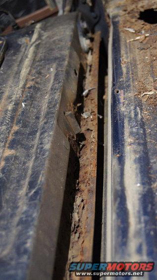 rusted out section of a vehicle's floor pan, showing significant corrosion