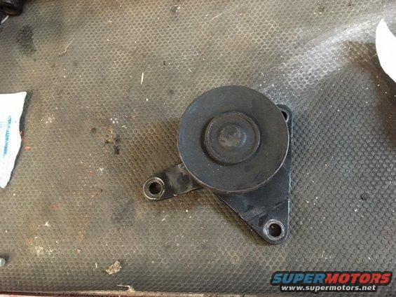 Black idler pulley bracket with a roller on a textured surface