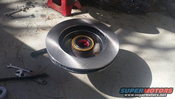 new brake rotor with bearing packed with red grease, tools on concrete