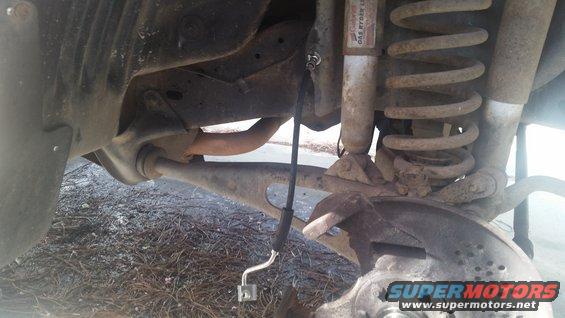 Vehicle suspension and brake parts, including a coil spring and shock absorber. A brake line is visible